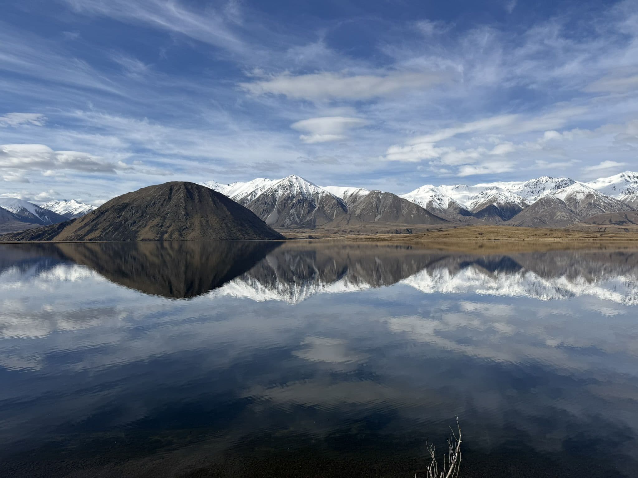 Snow-covered Southern Alps reflected in the still water of Lake Heron in the Canterbury high country