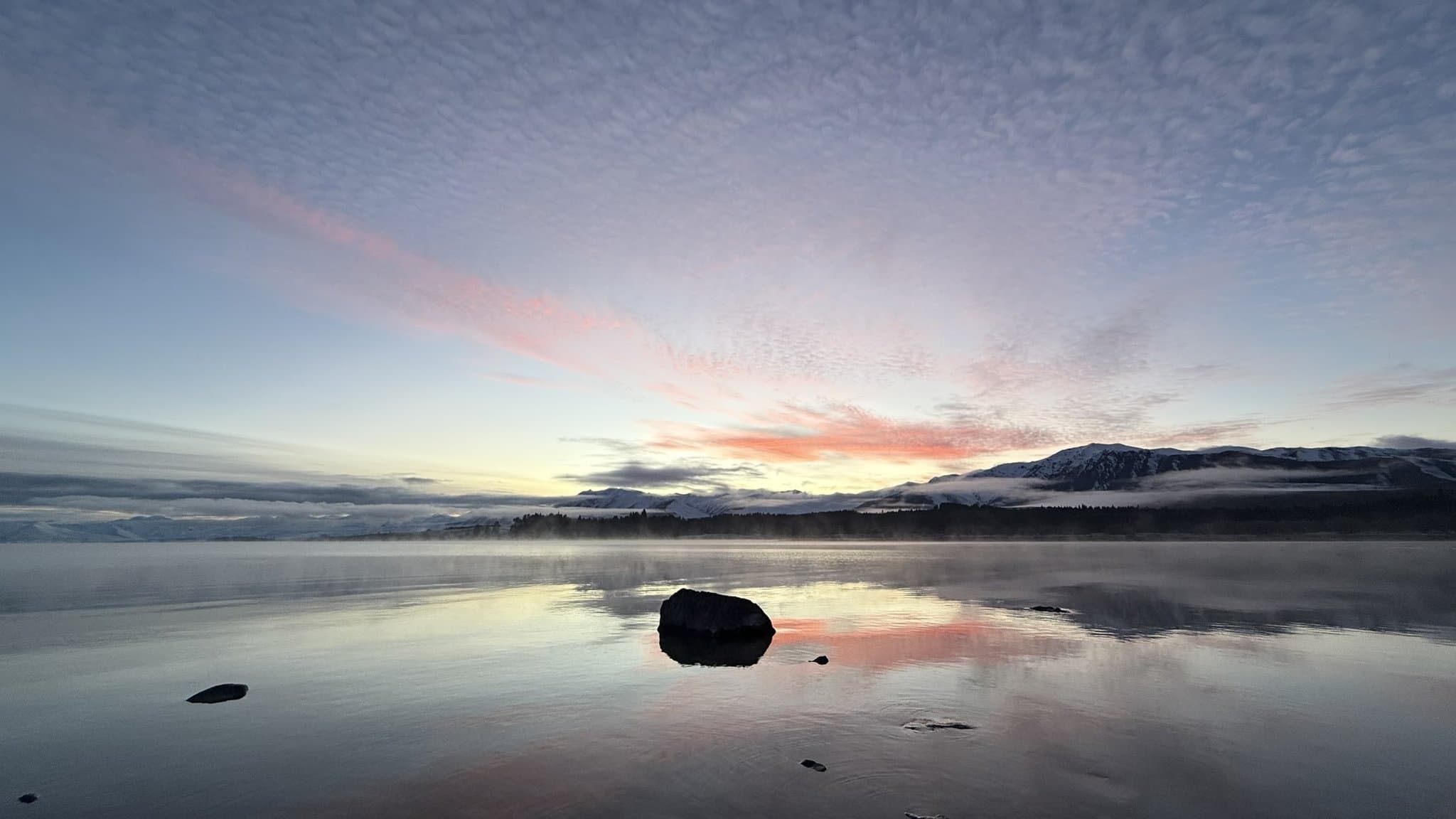 Warm sunset light over the still water and mountains of Lake Tekapo